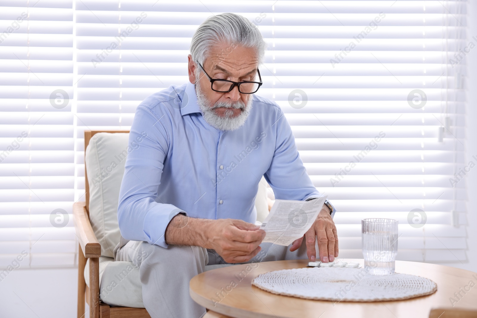 Photo of Senior man reading medicine instruction at home