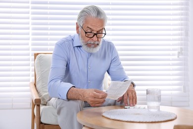 Photo of Senior man reading medicine instruction at home