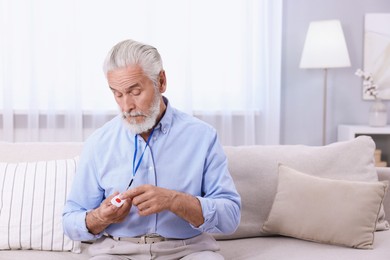 Photo of Senior man pressing emergency call button at home