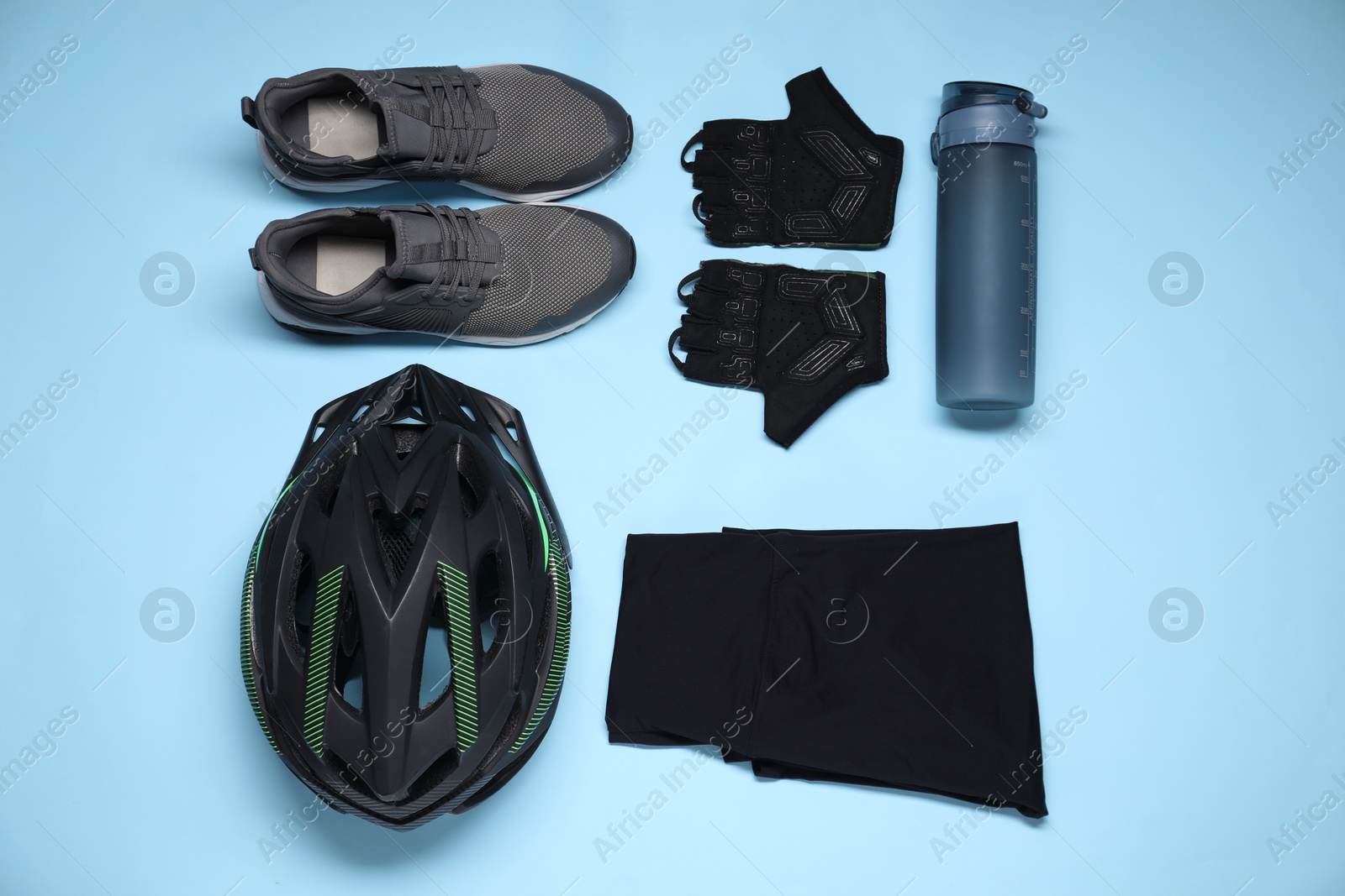 Photo of Bicycle helmet, sportswear, sneakers and thermo bottle on light blue background, flat lay