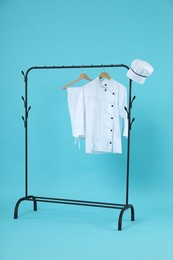 Chef's uniform on clothing rack against light blue background