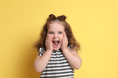 Photo of Portrait of happy girl on yellow background. Adorable child