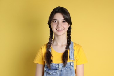 Photo of Portrait of smiling teenage girl on yellow background