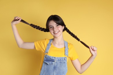 Portrait of smiling teenage girl on yellow background