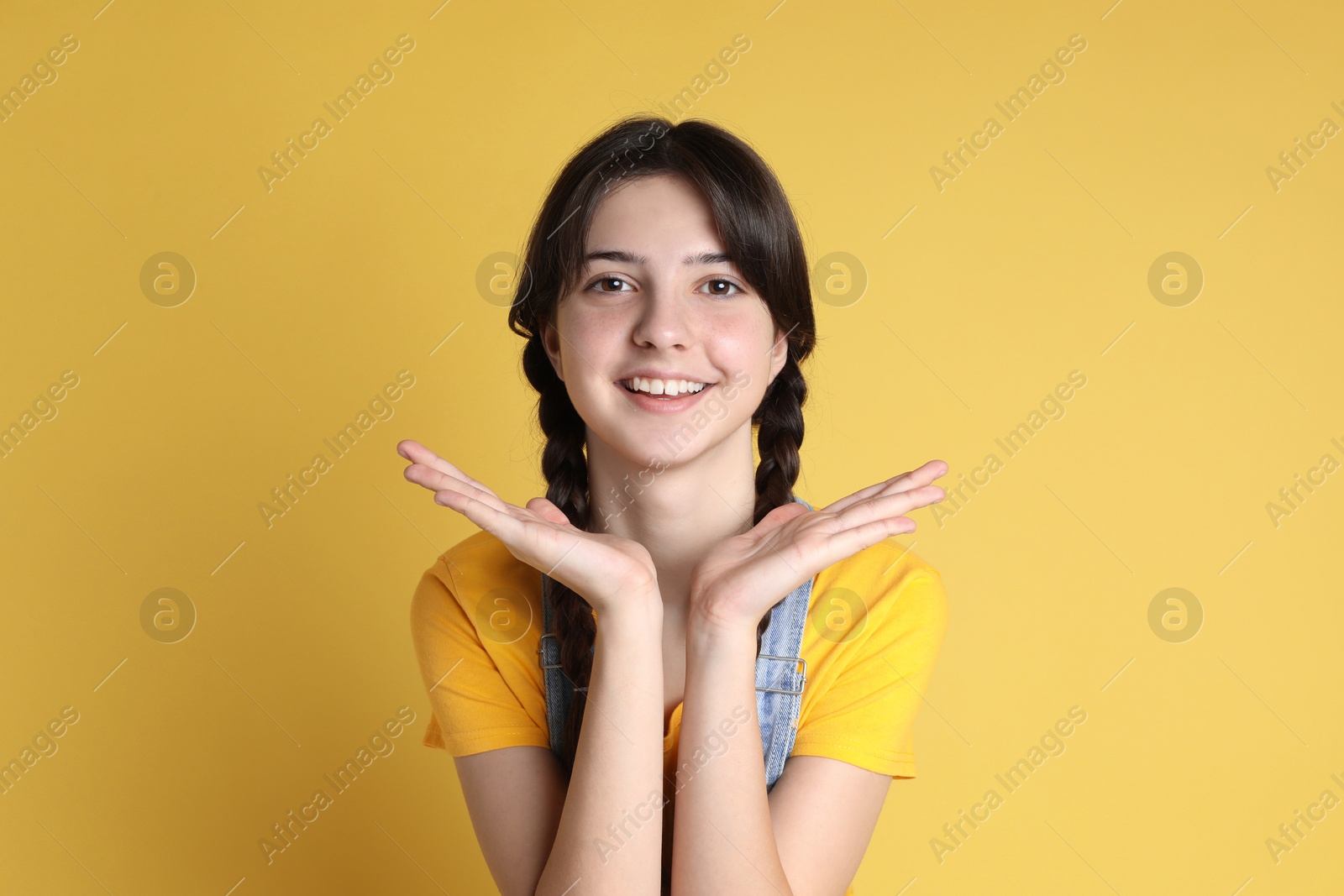 Photo of Portrait of smiling teenage girl on yellow background