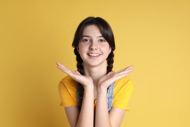 Photo of Portrait of smiling teenage girl on yellow background