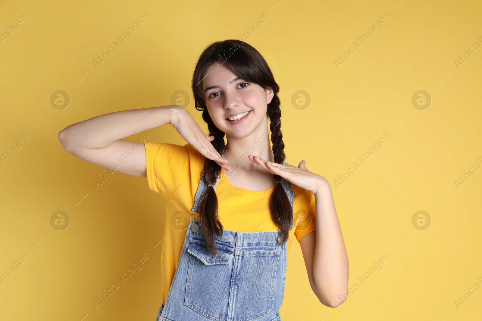 Photo of Portrait of smiling teenage girl on yellow background