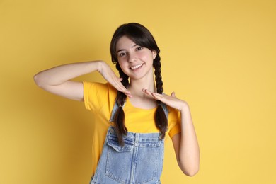 Portrait of smiling teenage girl on yellow background