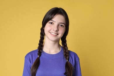 Photo of Portrait of smiling teenage girl on yellow background