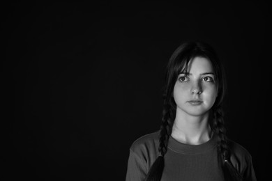 Photo of Portrait of teenage girl on dark background, space for text. Black and white effect