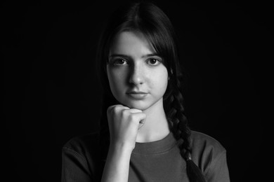 Portrait of teenage girl on dark background. Black and white effect