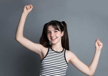 Portrait of smiling teenage girl on grey background