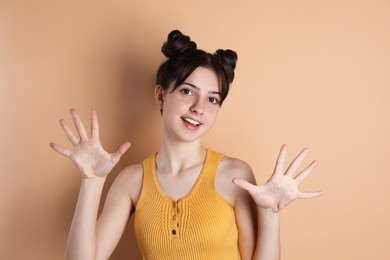 Photo of Portrait of happy teenage girl gesturing on beige background