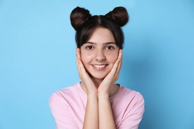 Portrait of smiling teenage girl on light blue background