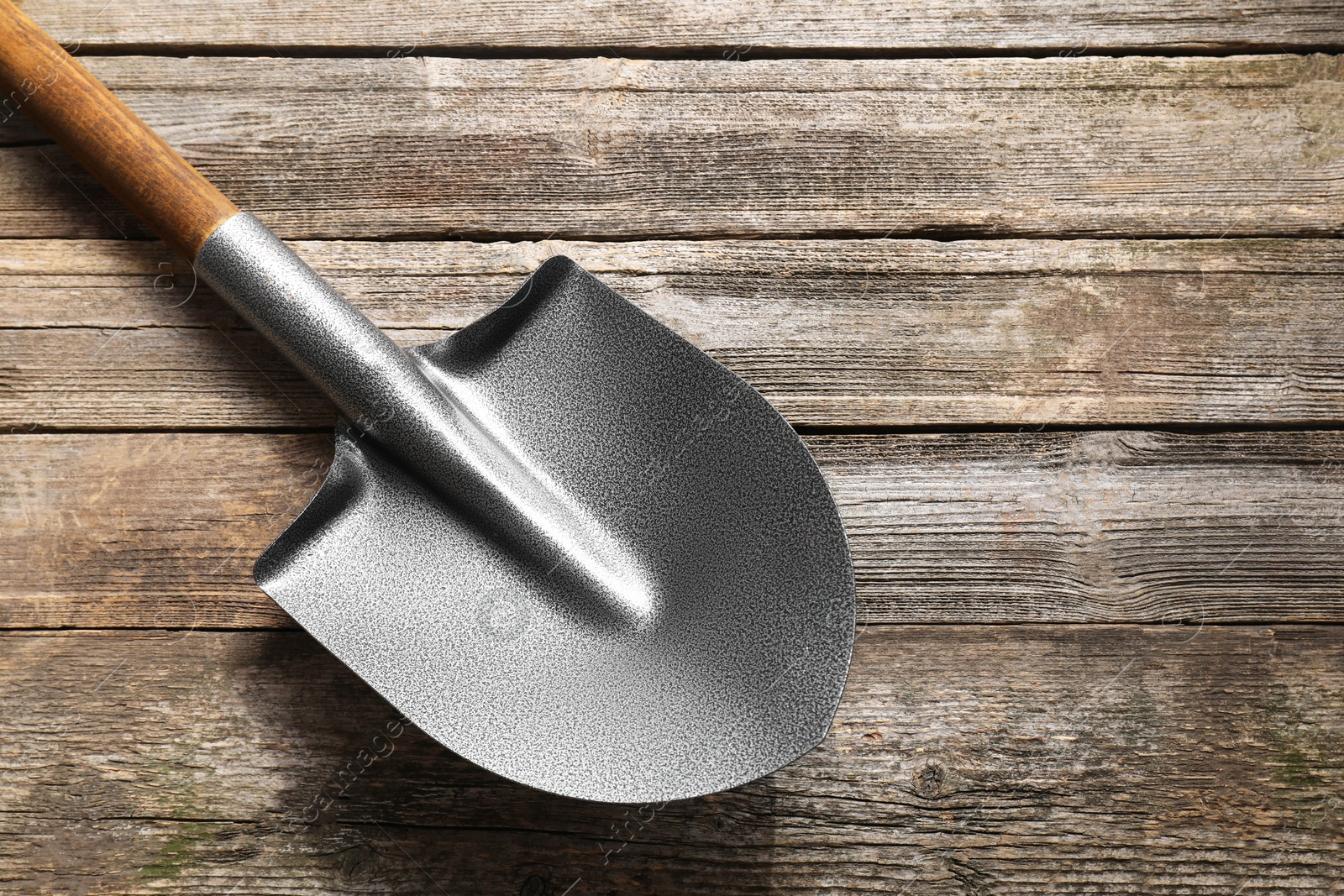 Photo of Metal shovel on wooden table, top view. Space for text