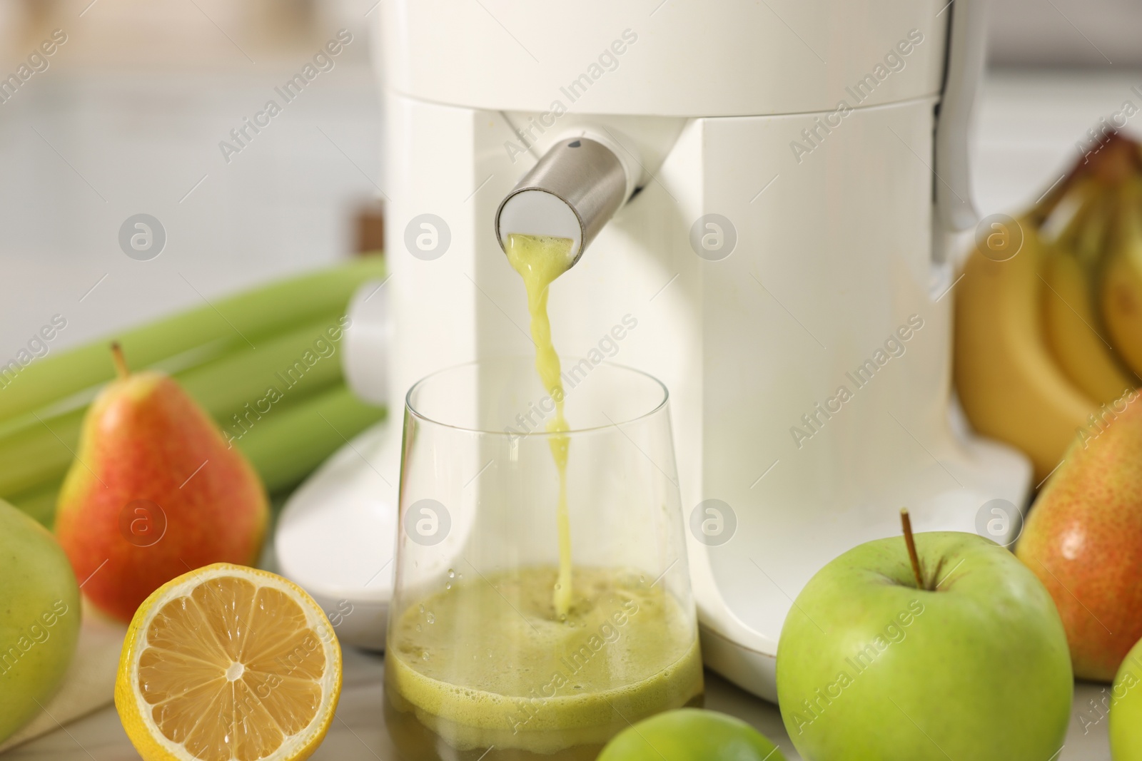 Photo of Modern juicer, fruits and glass on white table, closeup