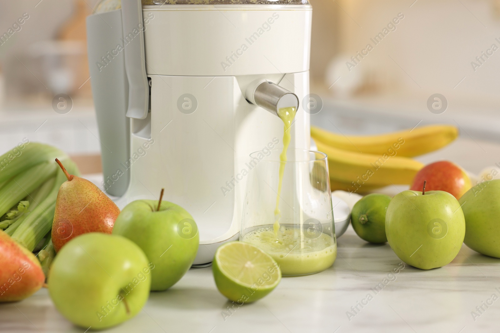 Photo of Modern juicer, fruits and glass on white marble table, closeup