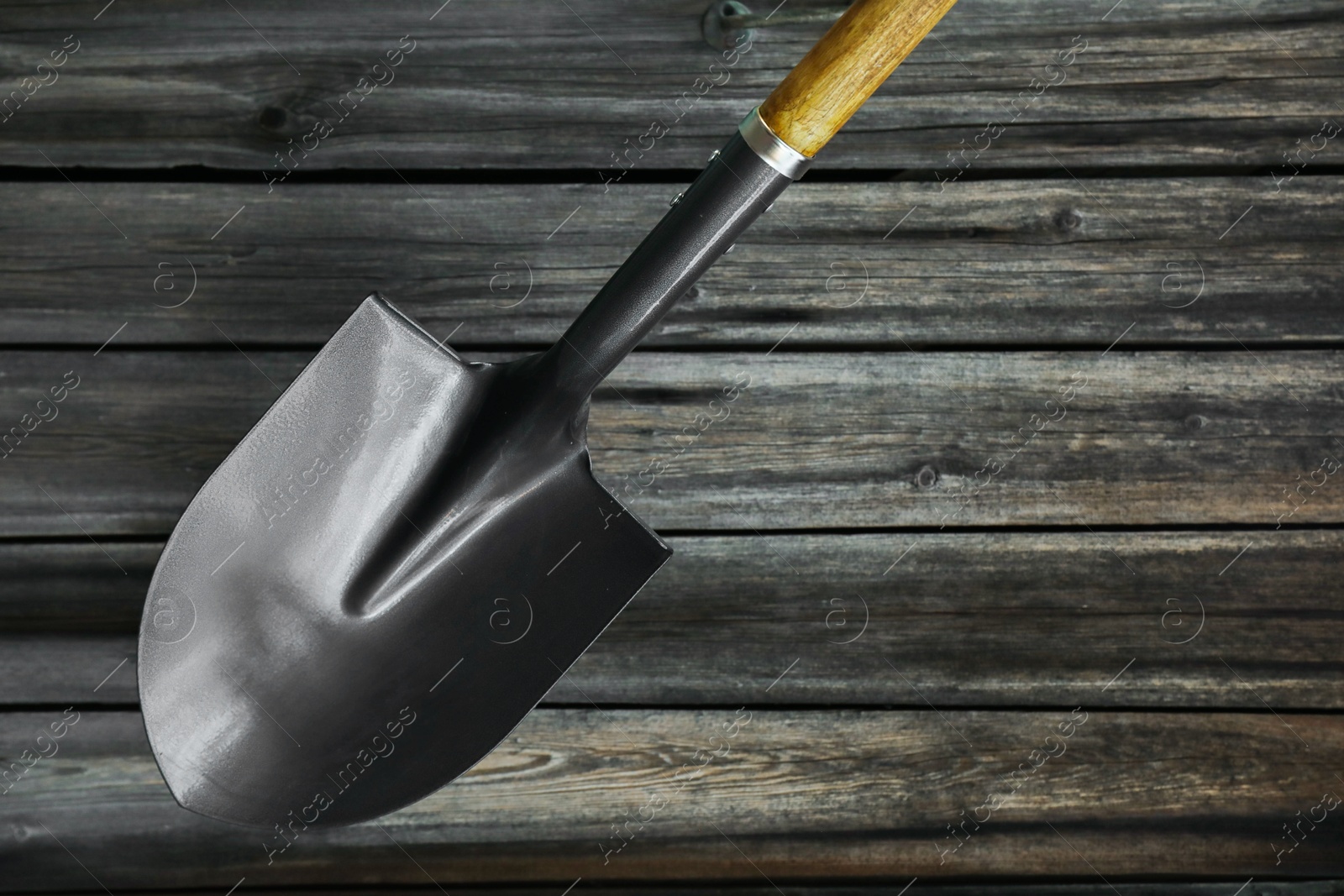 Photo of Metal shovel on black wooden surface, top view