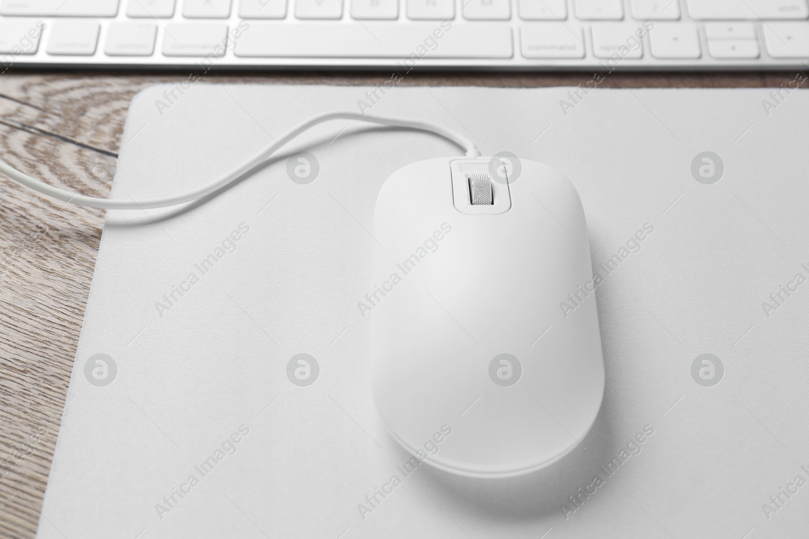 Photo of Computer mouse with mousepad and keyboard on wooden table