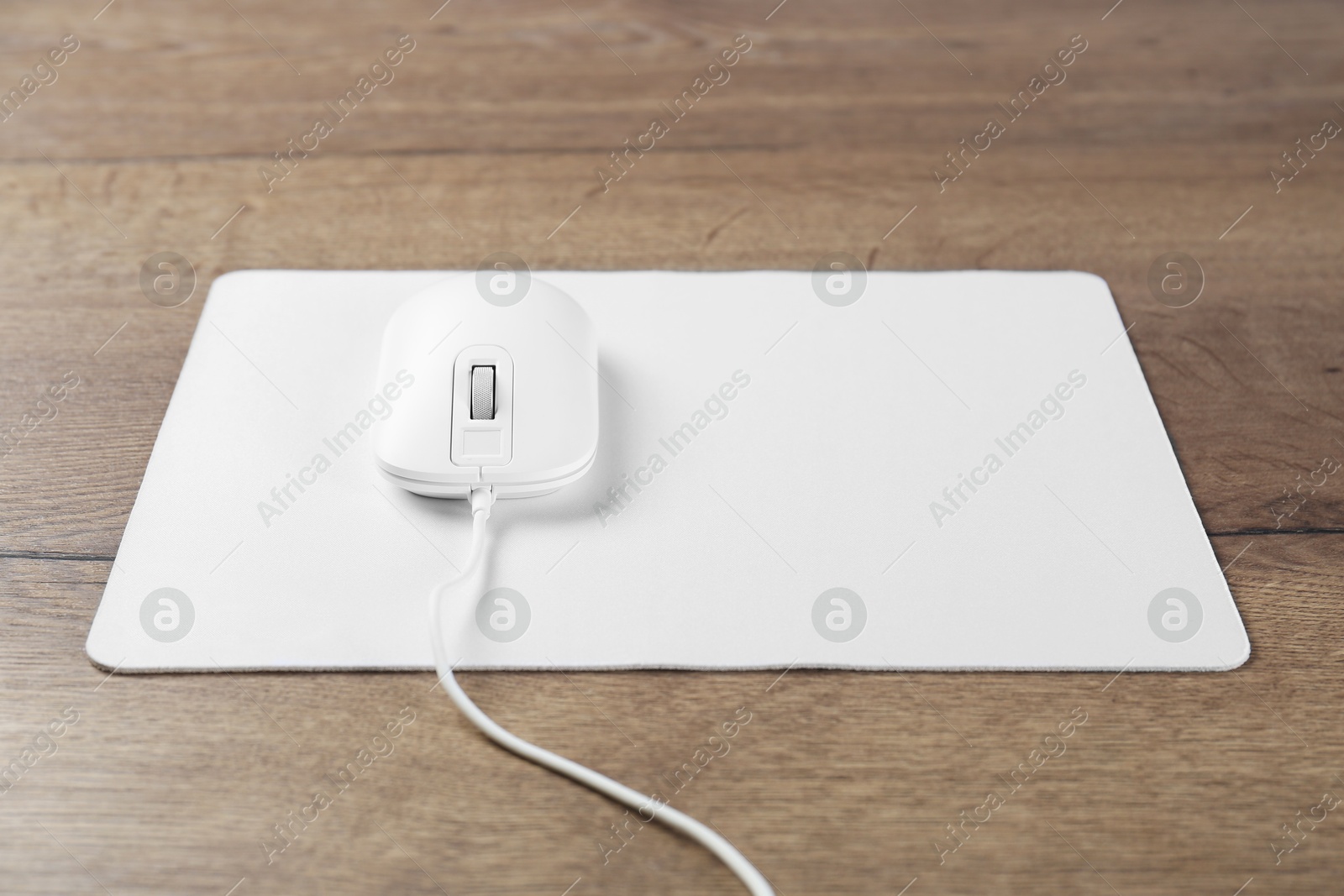 Photo of Computer mouse with mousepad on wooden table