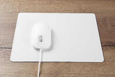 Photo of Computer mouse with mousepad on wooden table