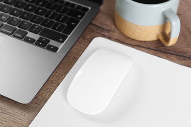 Photo of Computer mouse with mousepad and laptop on wooden table