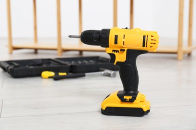 Cordless electric screwdriver and other tools on floor in room