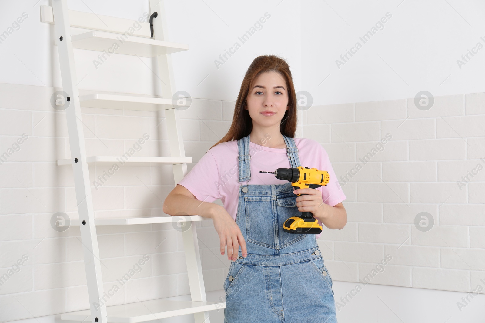 Photo of Woman with electric screwdriver indoors. Assembling furniture