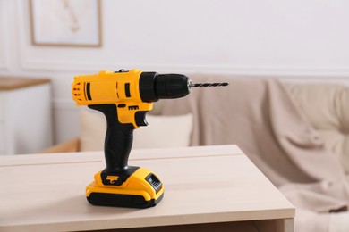 Photo of Cordless electric screwdriver on wooden table at home