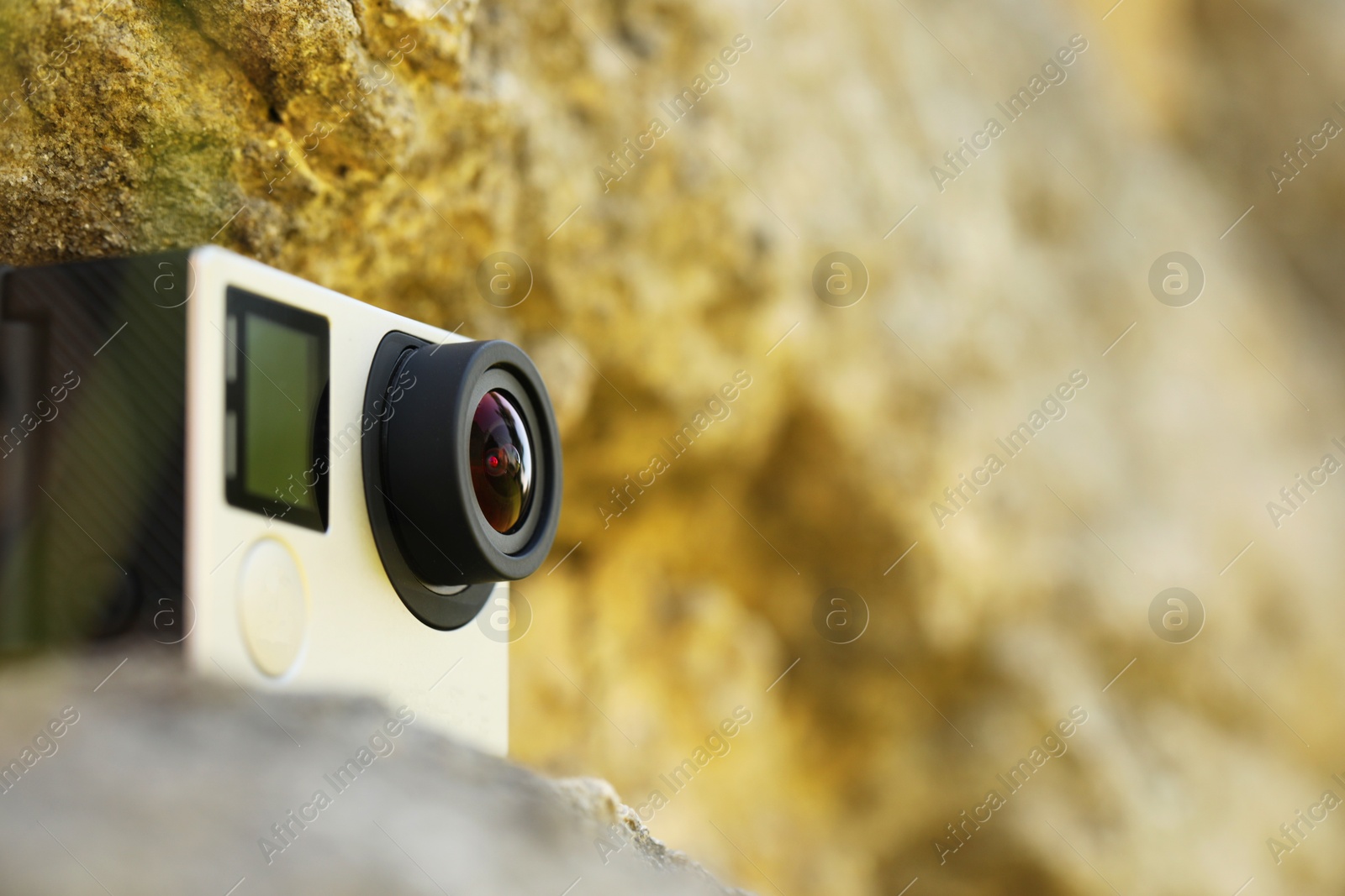 Photo of Modern action camera on stone, closeup. Space for text