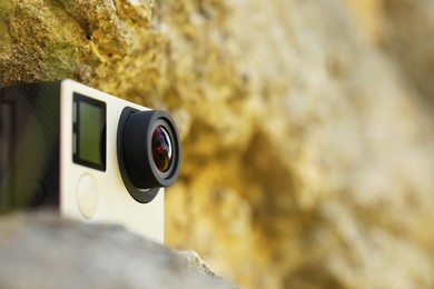 Photo of Modern action camera on stone, closeup. Space for text