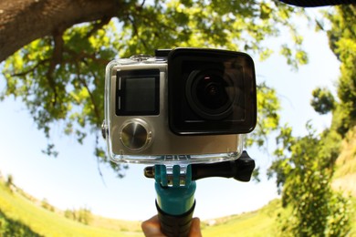 Man with modern action camera and monopod outdoors, closeup. Fisheye lens effect