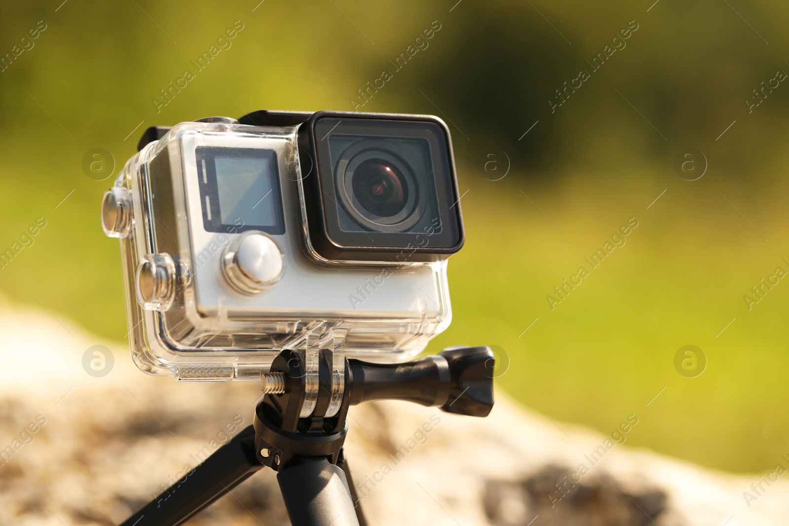 Photo of Modern action camera with tripod outdoors, closeup