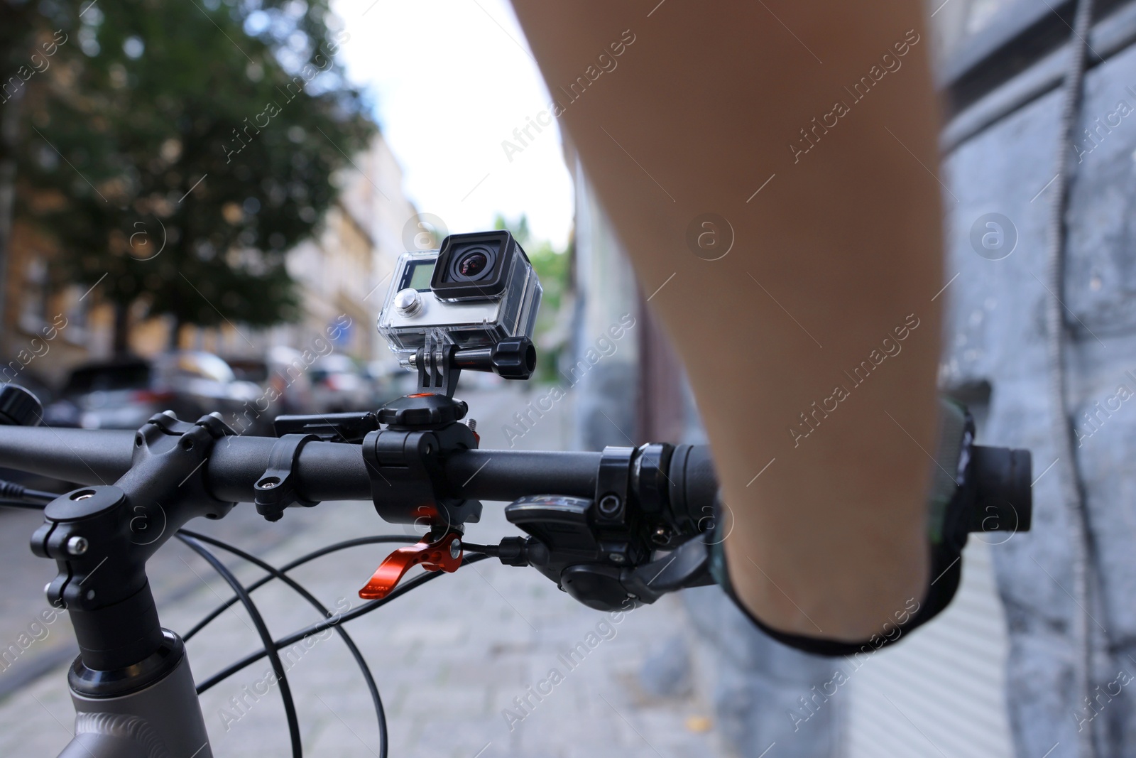 Photo of Man riding bicycle with modern action camera outdoors, closeup