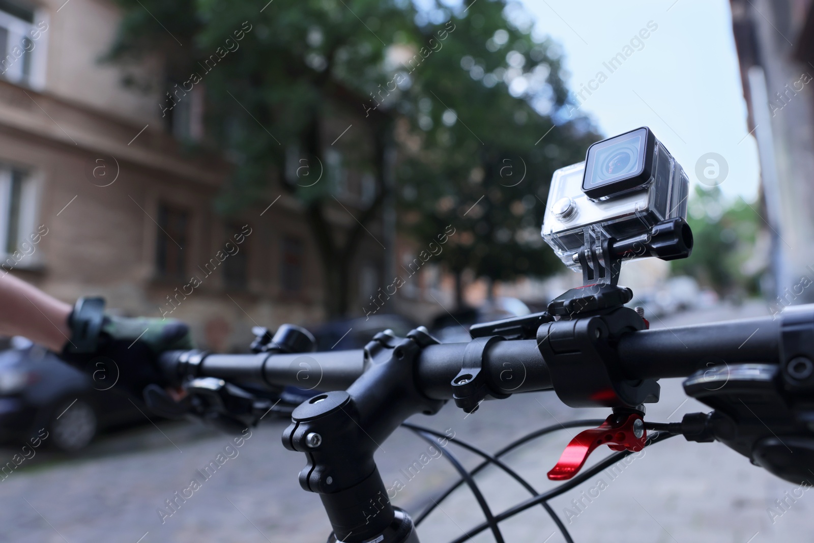 Photo of Modern action camera with mount on bicycle outdoors, closeup