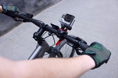 Man riding bicycle with modern action camera outdoors, closeup