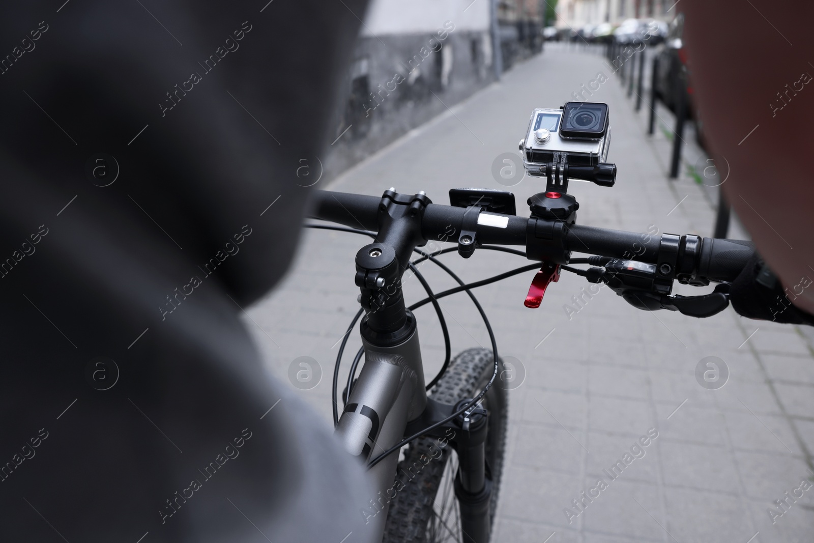 Photo of Man riding bicycle with modern action camera outdoors, closeup