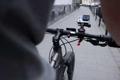 Man riding bicycle with modern action camera outdoors, closeup