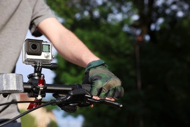 Man riding bicycle with modern action camera outdoors, closeup