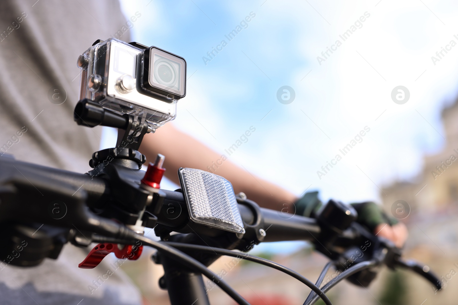 Photo of Man riding bicycle with modern action camera outdoors, closeup