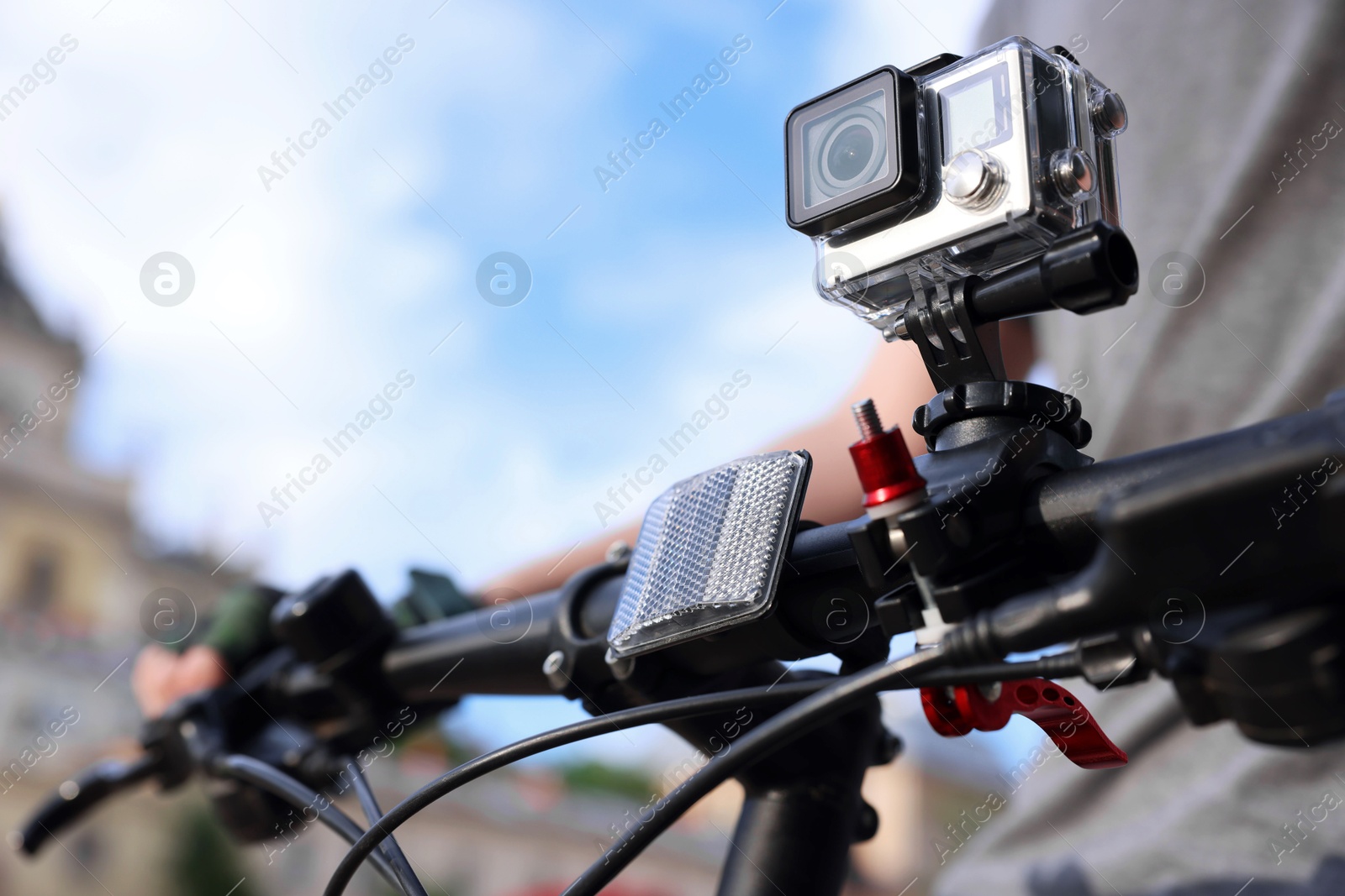 Photo of Man riding bicycle with modern action camera outdoors, closeup