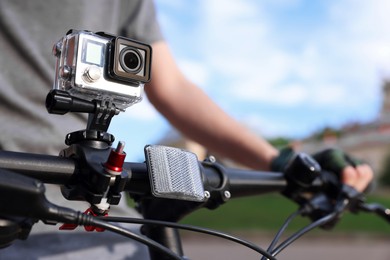 Man riding bicycle with modern action camera outdoors, closeup