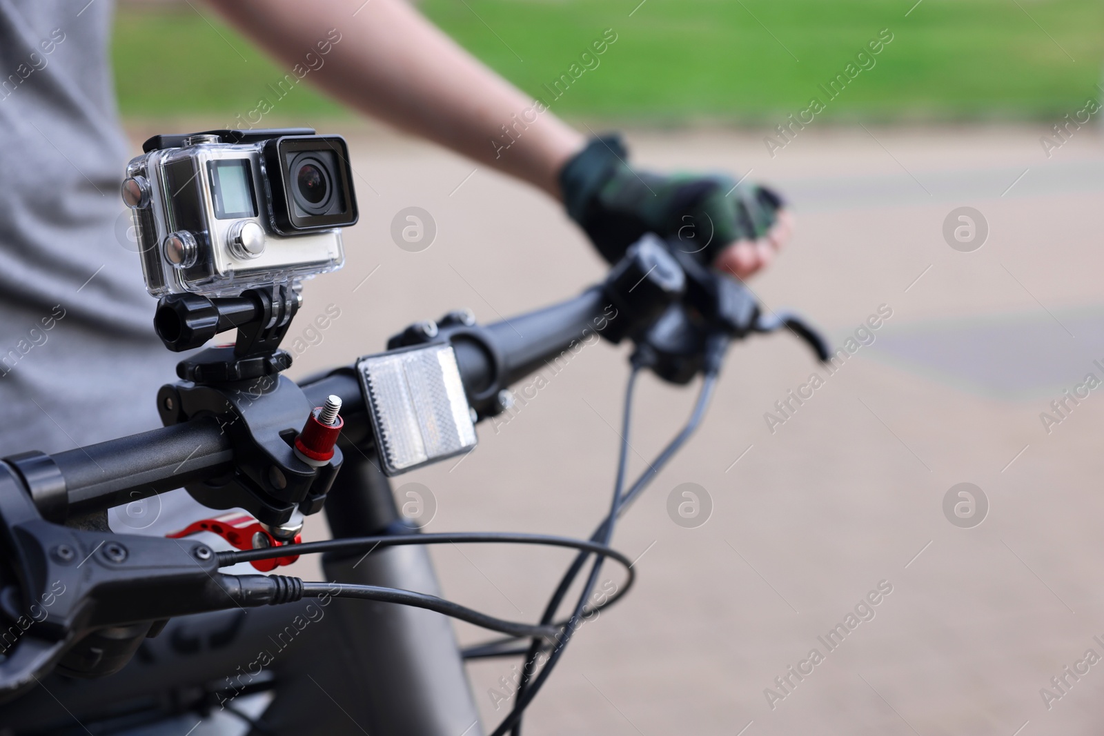 Photo of Man riding bicycle with modern action camera outdoors, closeup. Space for text