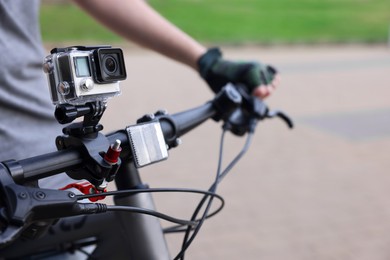 Man riding bicycle with modern action camera outdoors, closeup. Space for text