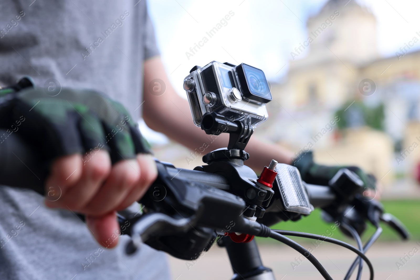 Photo of Man riding bicycle with modern action camera outdoors, closeup