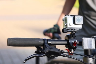 Man near bicycle with modern action camera outdoors, closeup