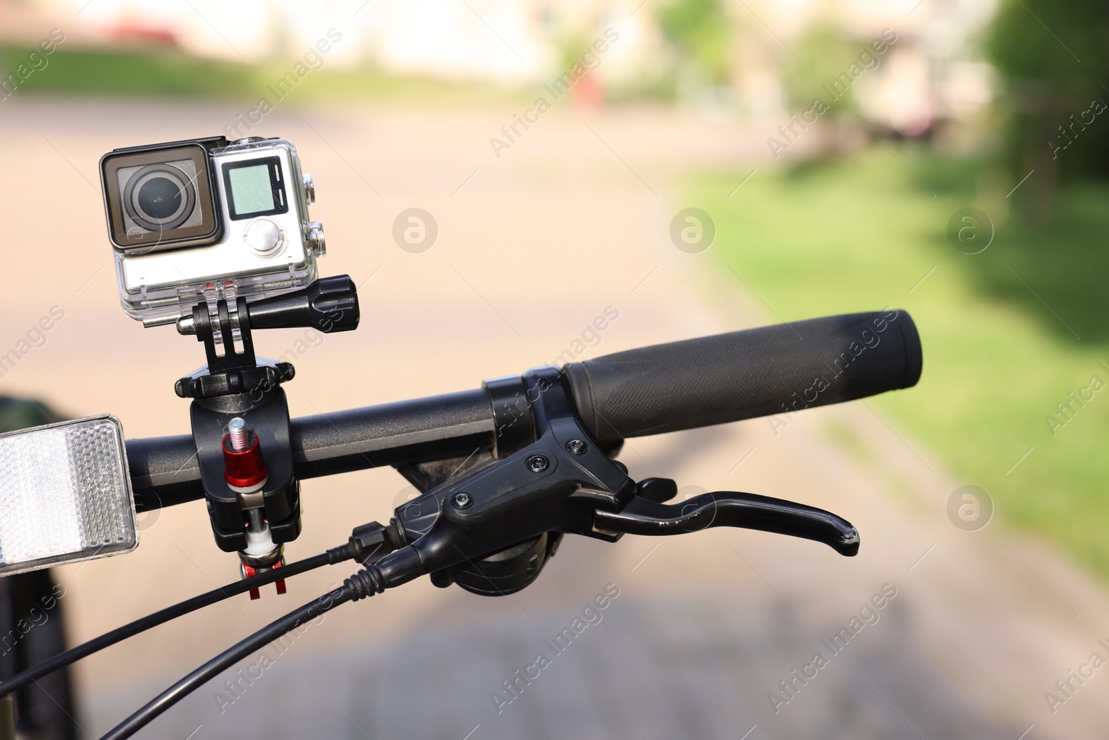 Photo of Modern action camera with mount on bicycle outdoors, closeup