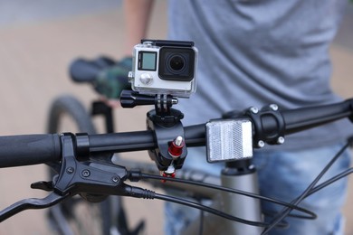 Photo of Man near bicycle with modern action camera outdoors, closeup