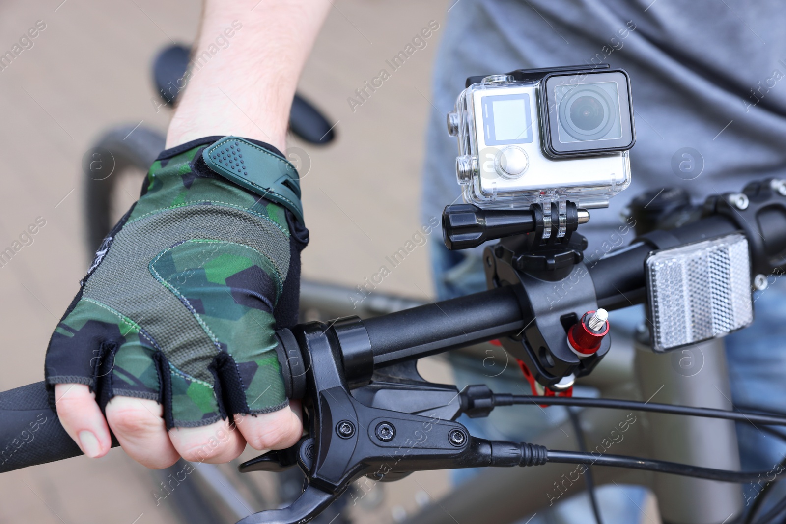 Photo of Man near bicycle with modern action camera outdoors, closeup