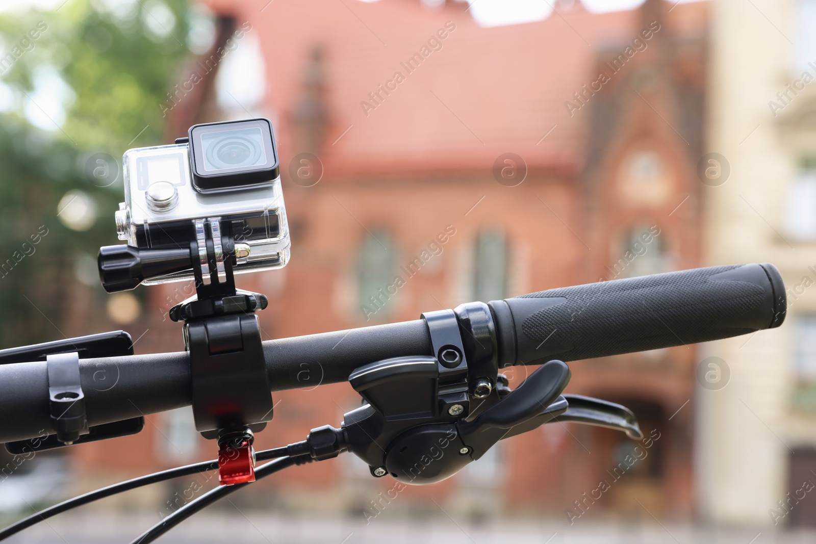 Photo of Modern action camera with mount on bicycle outdoors, closeup